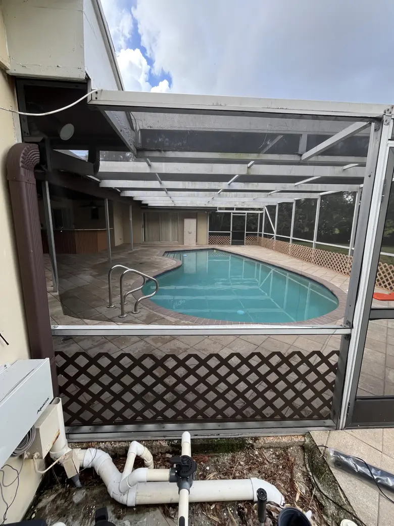 Before: a torn screen panel sagging at the pool cage corner